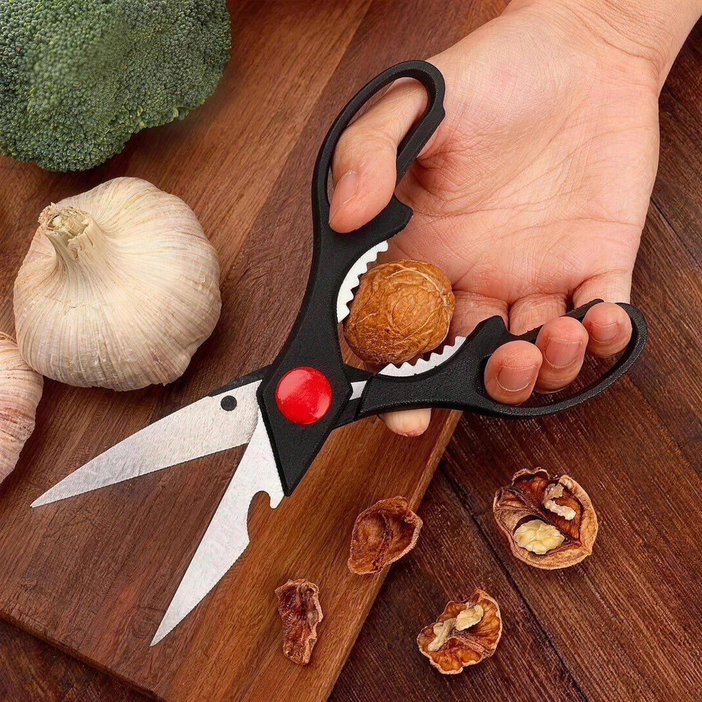 Hand holding the kitchen scissors with a walnut in the nutcracker grip built into the handle