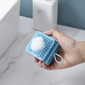 Scalp massage brush held in hand with shampoo lather