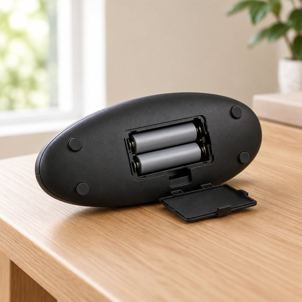 Battery compartment open on the underside of the can opener, holding two AA batteries (not included)