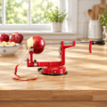 3-in-1 apple peeler on a butcher-block counter peeling an apple in one long strip